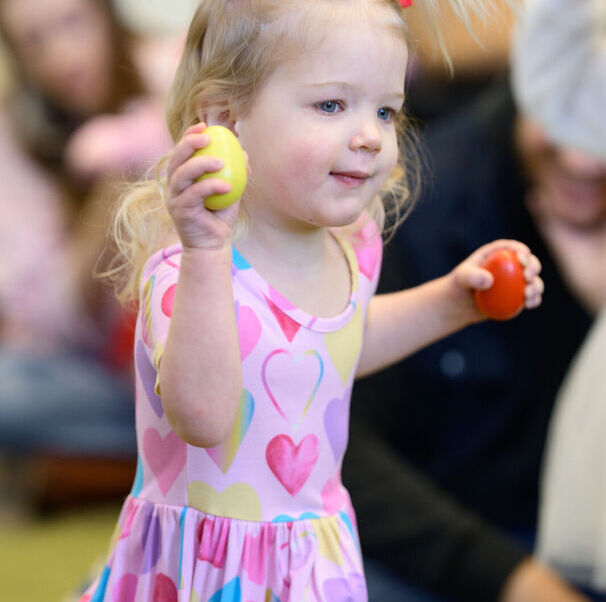 Young child holding egg shakers in Born to Play room