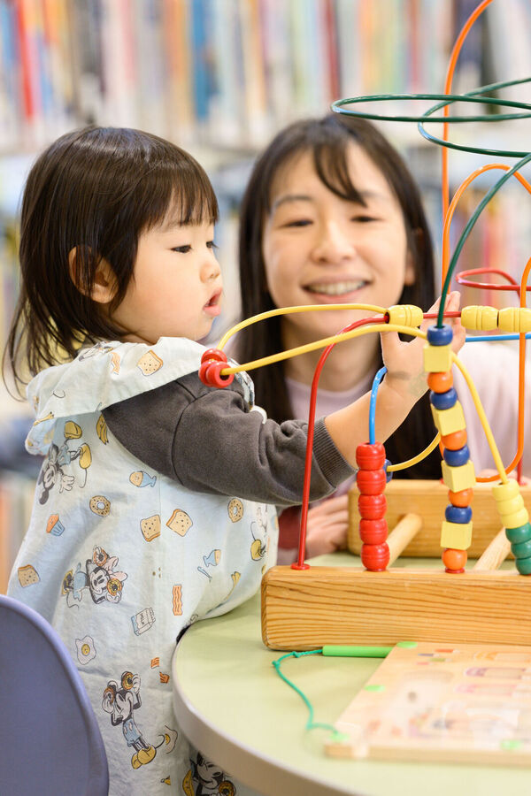 Child using a bead maze with parent looking on